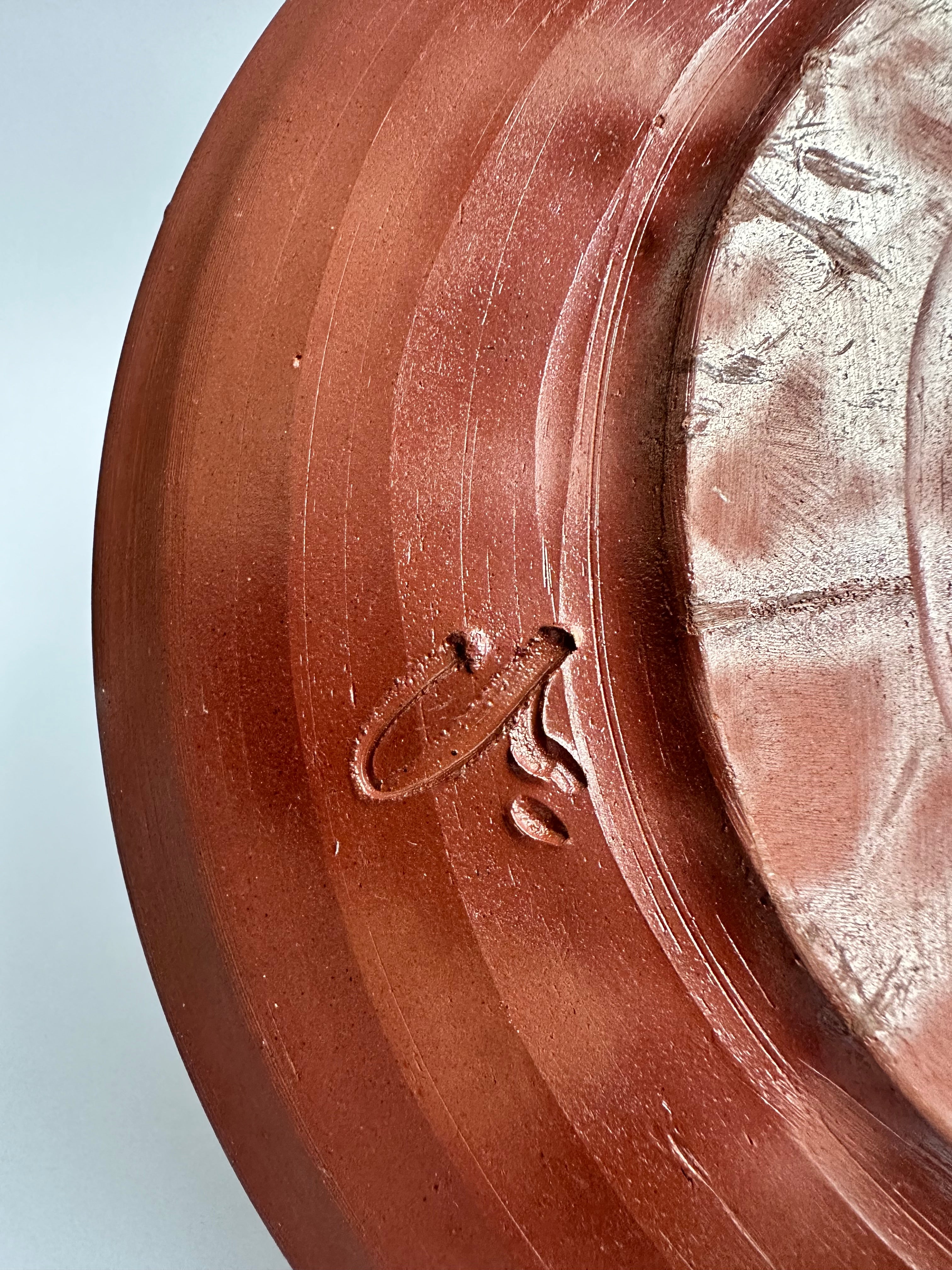 Back of vintage Bizen pottery plate with artisan kiln mark and natural wood-fired ash patterns.