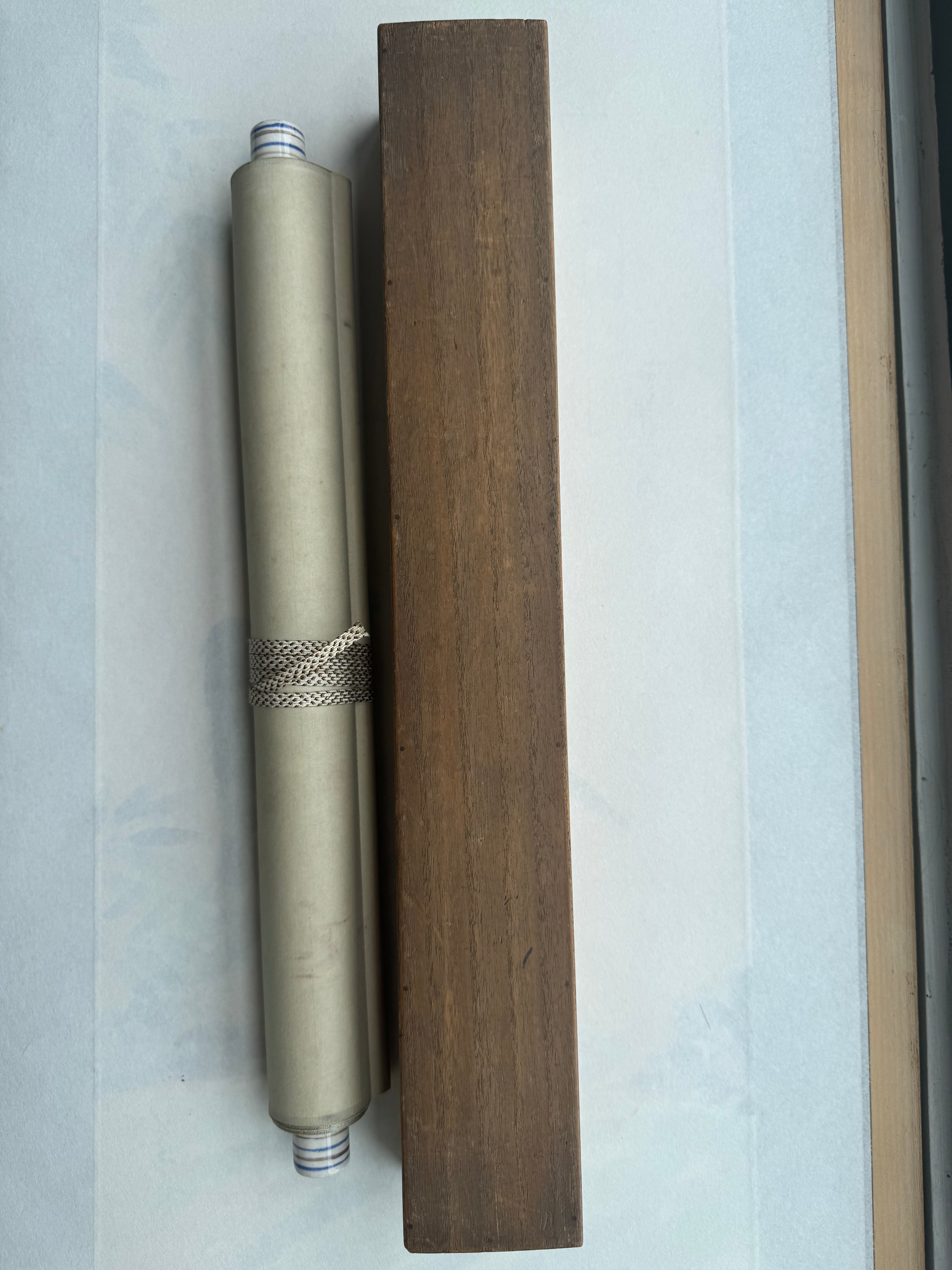 Metallic cylindrical object with decorative band on a wooden block against a light blue background
