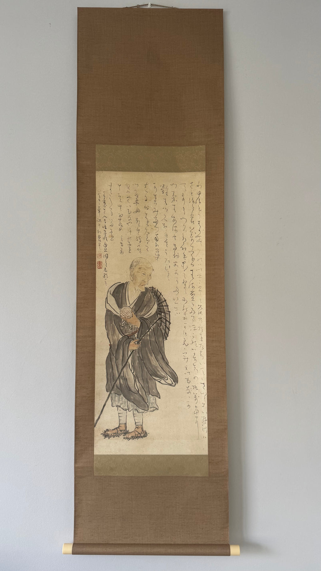 Traditional Japanese scroll with a figure and calligraphy on a plain background