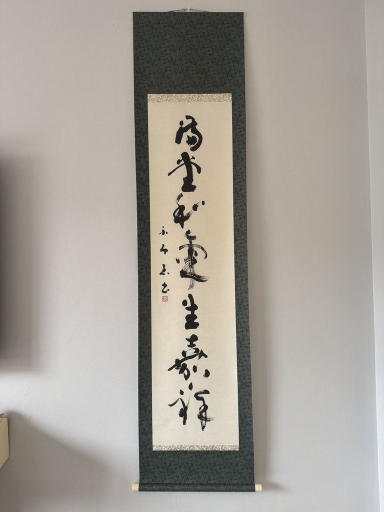 Vertical scroll with calligraphy on a gray wall