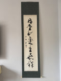 Vertical scroll with calligraphy on a gray wall