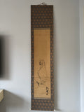 Traditional East Asian scroll with decorative border on a plain wall