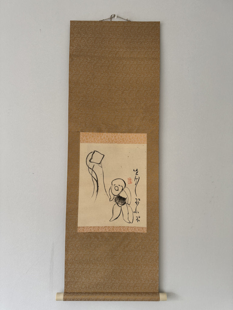 A traditional Japanese hanging scroll (kakemono) featuring a minimalist black ink sketch of a child holding a kite, mounted on a textured brown paper background with a light beige paper insert.