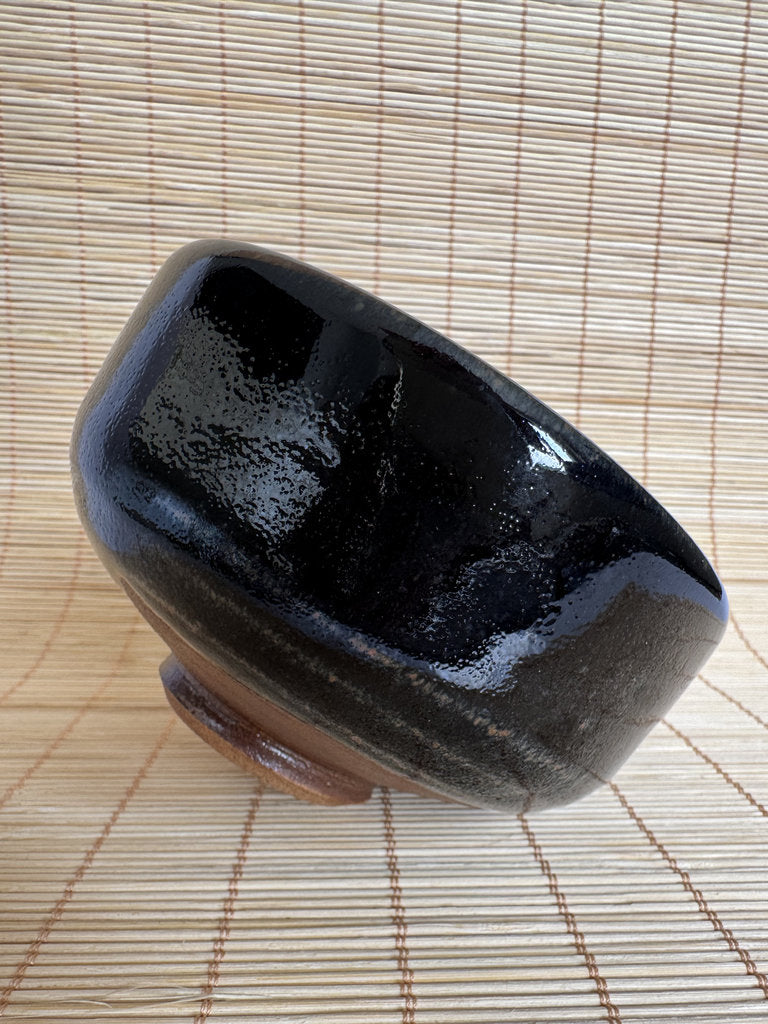 Black ceramic bowl on a woven mat
