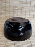 Black ceramic bowl on a woven mat