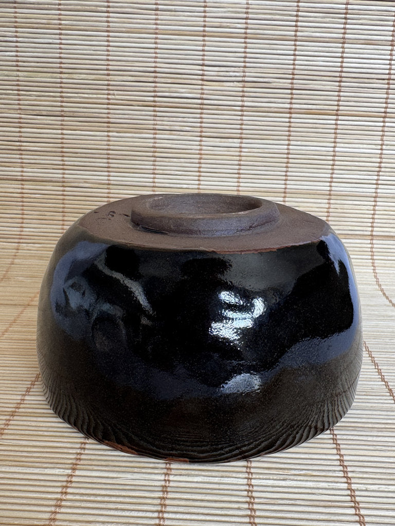 Black ceramic bowl on a woven mat