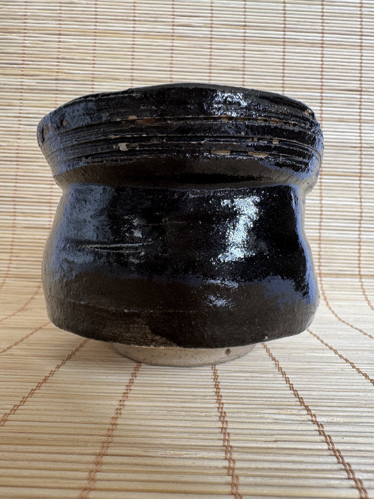 Black ceramic pot on a woven mat