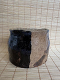 Ceramic pot with black and beige design on a woven mat background