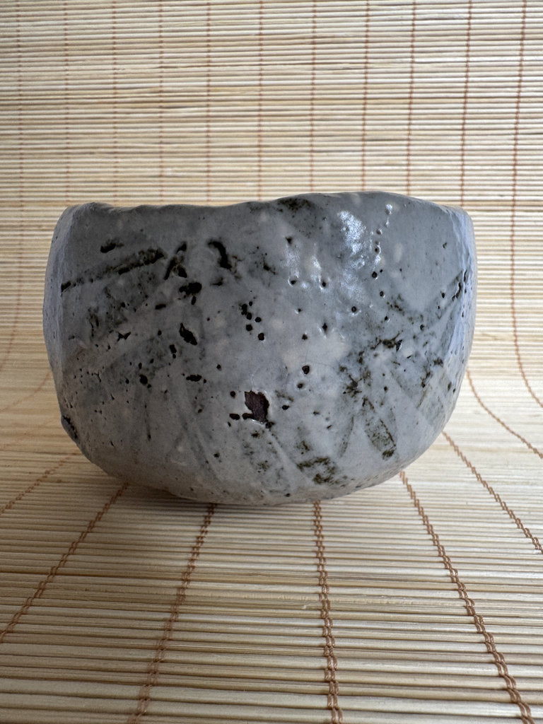 Ceramic bowl with textured surface on a woven mat