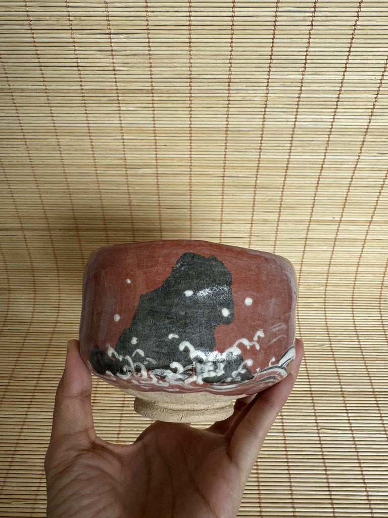 Ceramic bowl with artistic design held by a hand on a woven mat background