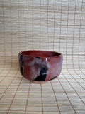 Red ceramic bowl on a woven mat