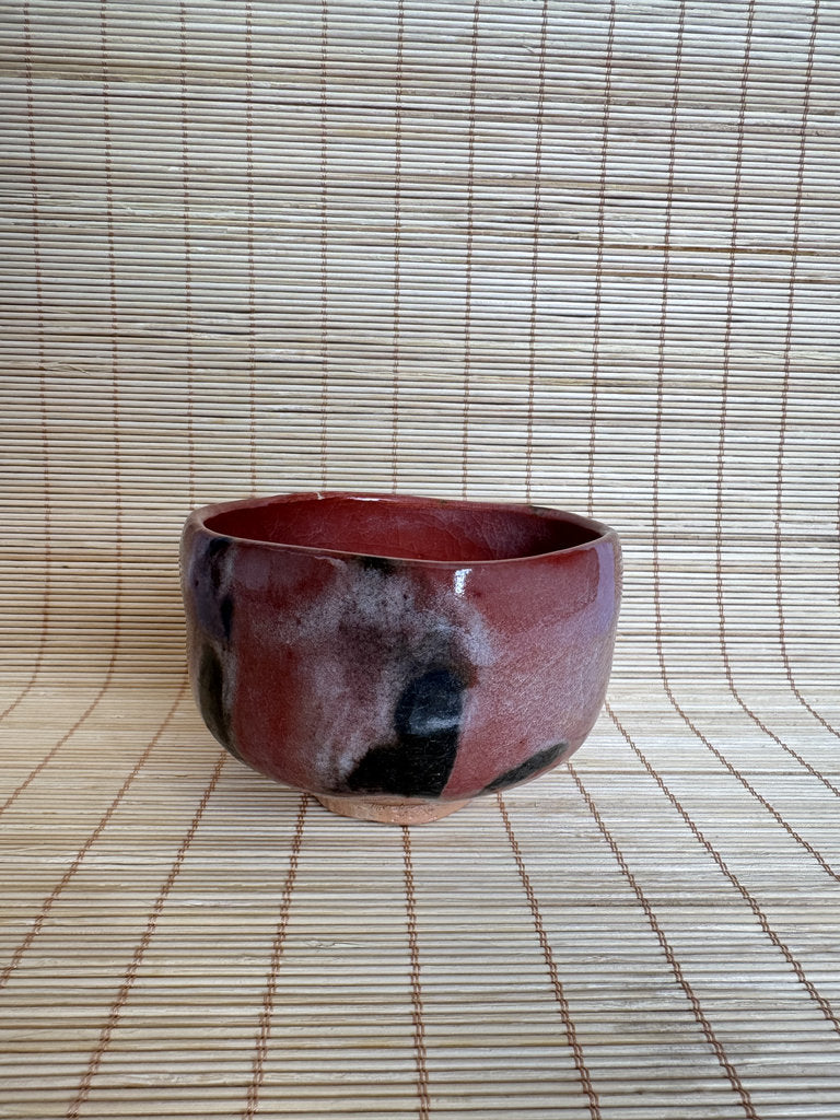 Red ceramic bowl on a woven mat