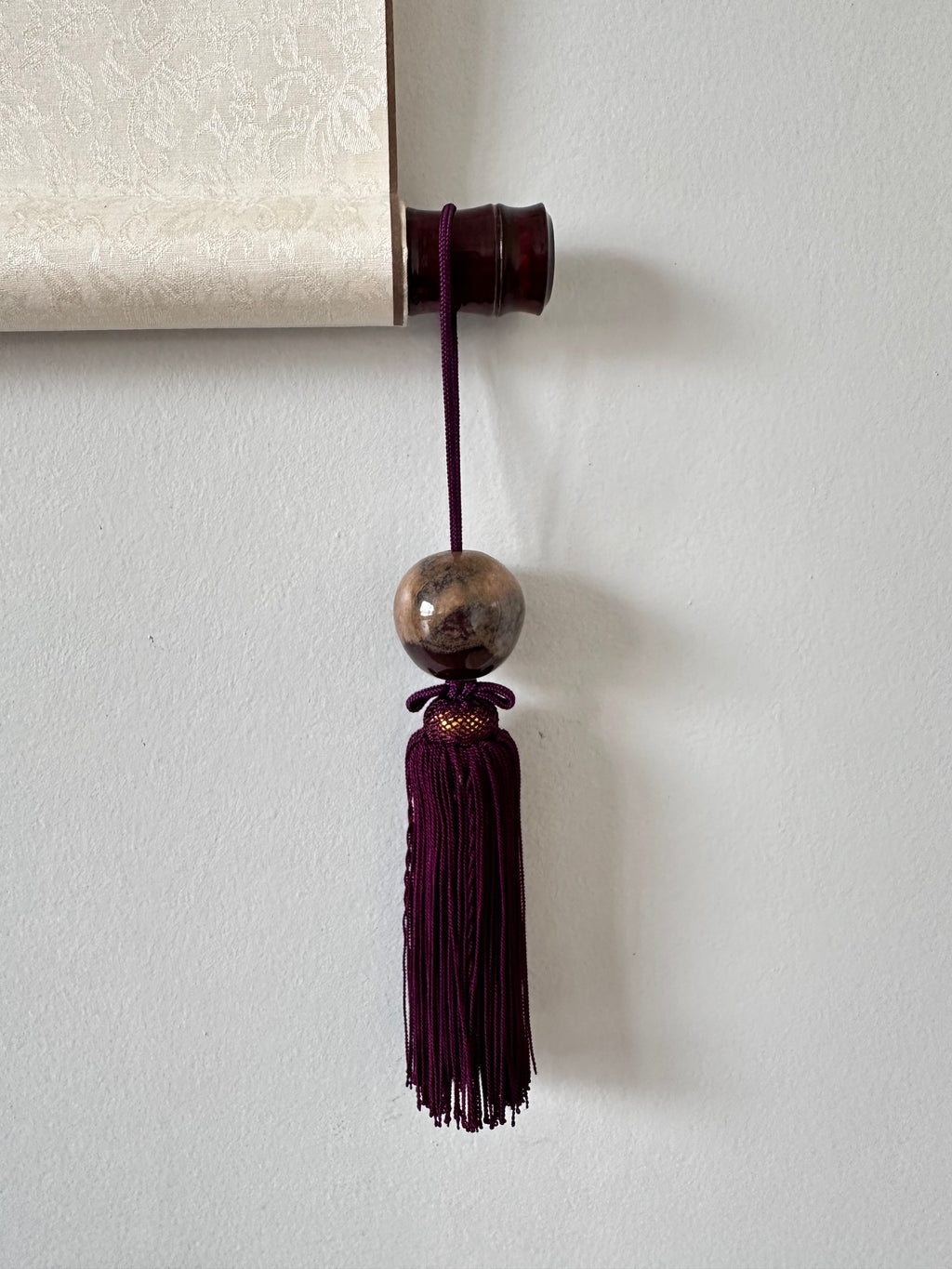 Decorative tassel with a bead on a white wall