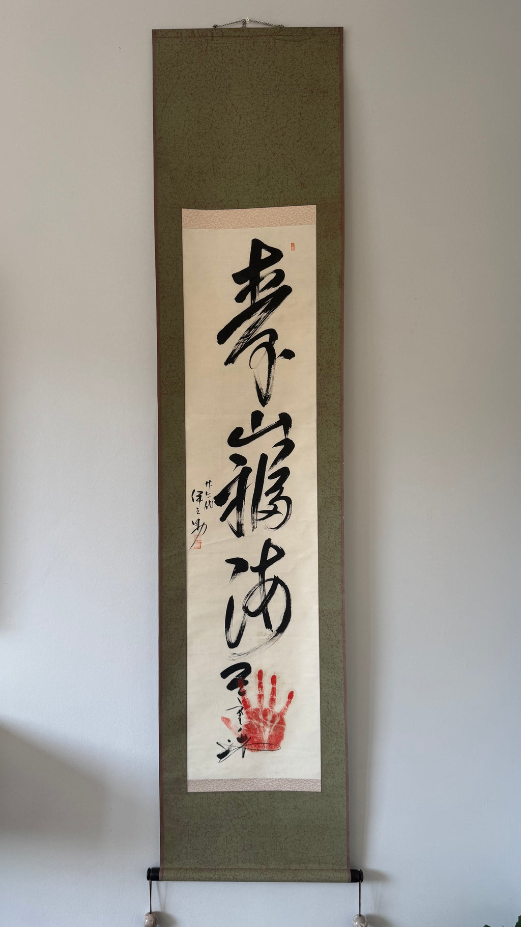 Calligraphy artwork on a wall with a handprint below