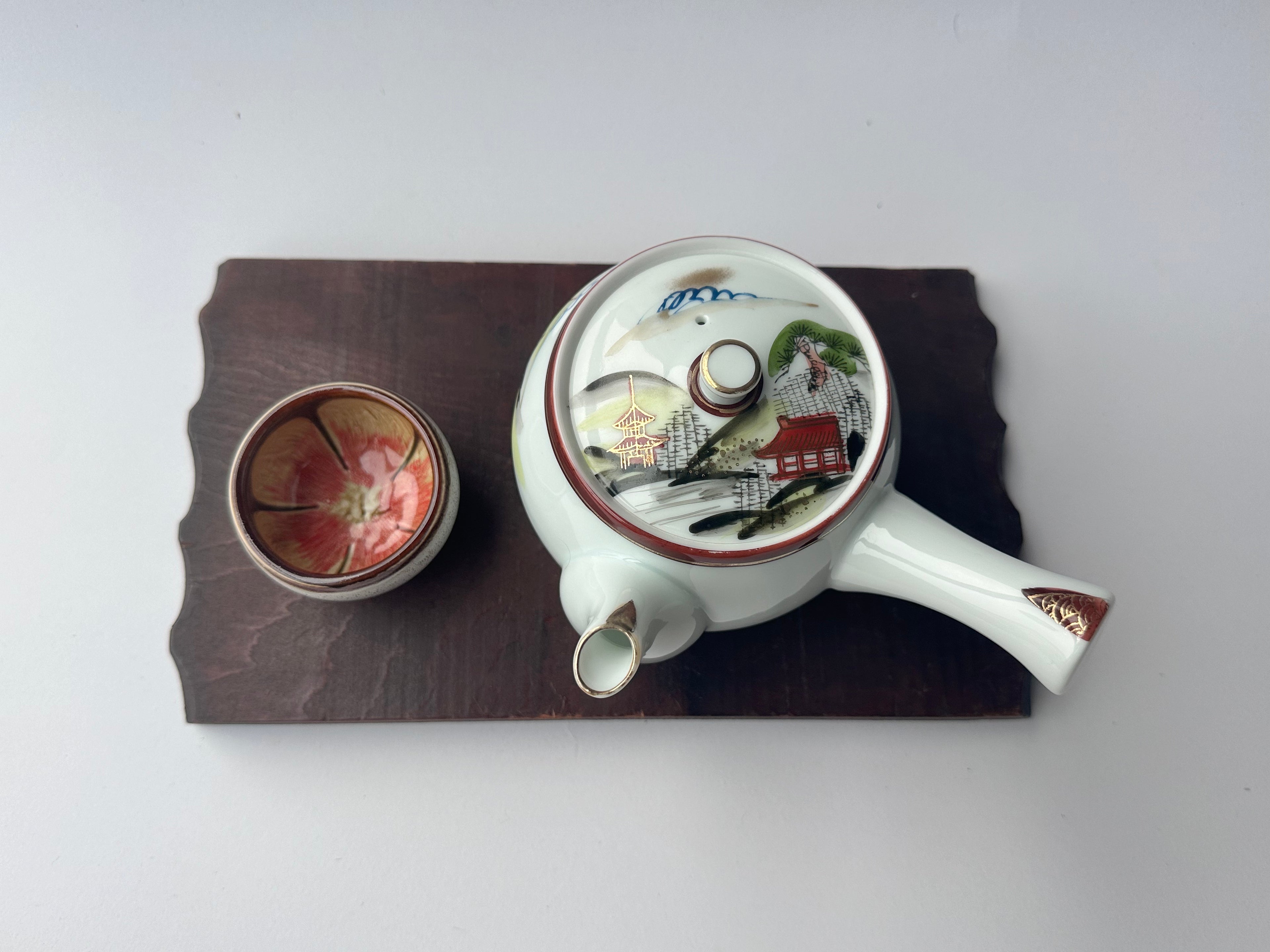 Decorative teapot with lid on a wooden board against a white background