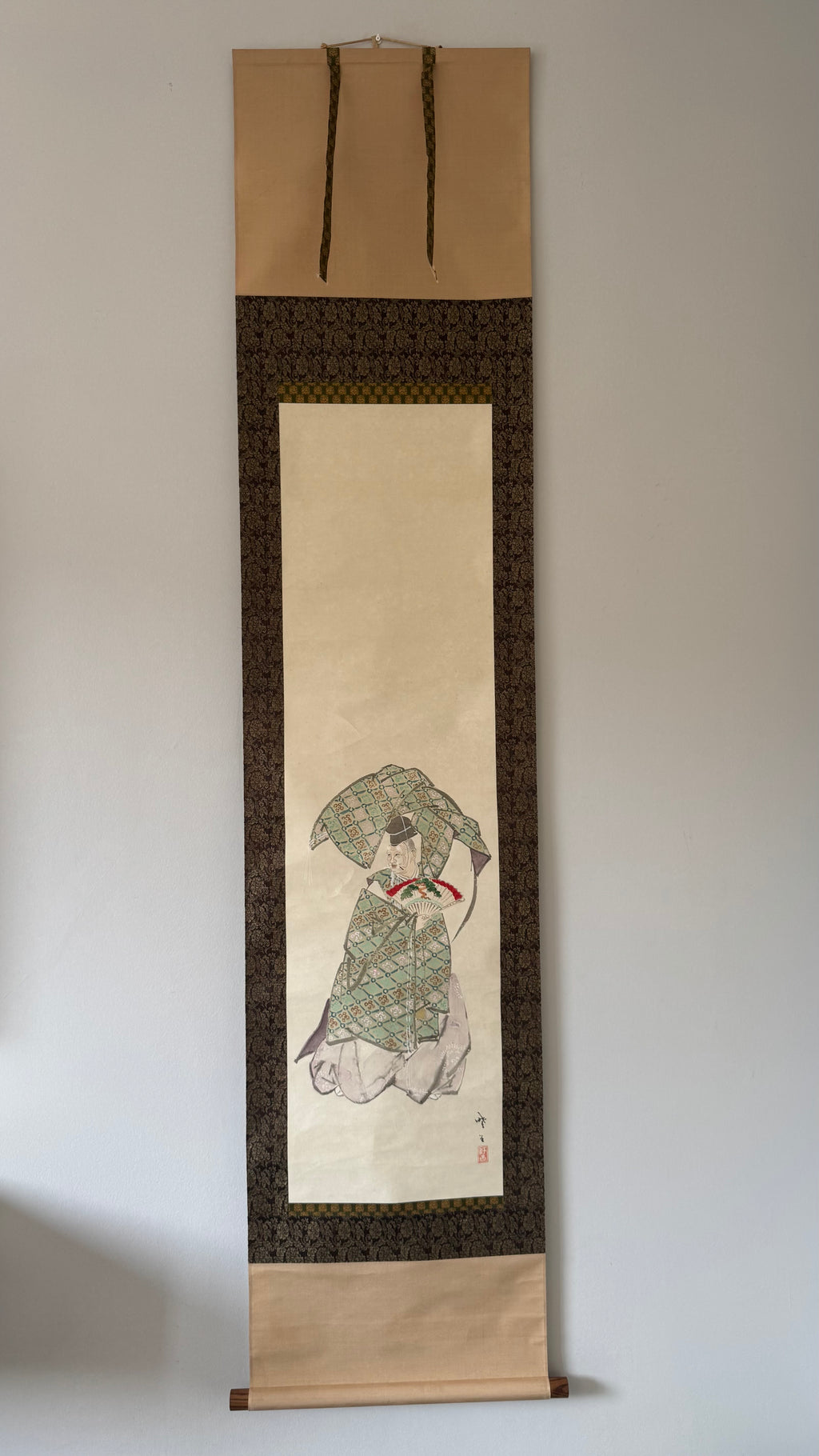 Traditional Japanese scroll with a woman holding an umbrella on a plain background