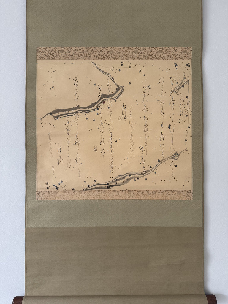 A traditional Japanese hanging scroll (kakejiku) featuring black ink calligraphy on a beige paper background, bordered by patterned bands and framed by a wide olive-green fabric margin.