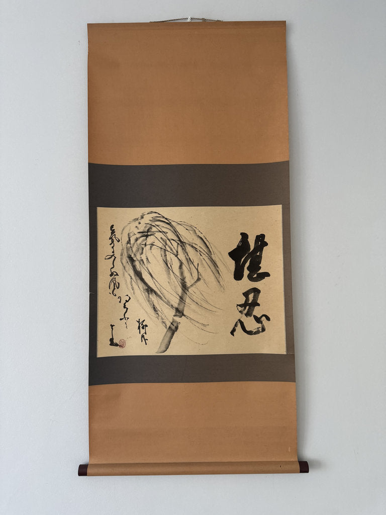 A traditional Japanese hanging scroll (kakemono) featuring black ink calligraphy and a brushstroke painting of a pine tree on a beige paper center, mounted on a brown paper roll with a dark brown band.