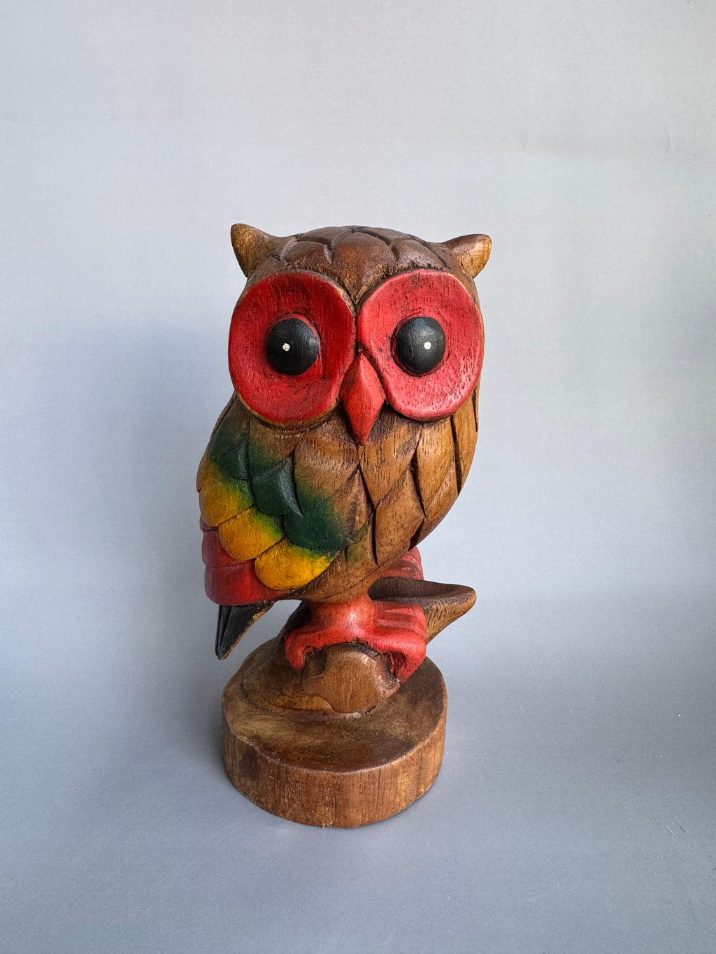 Wooden owl figurine with colorful face on a white background