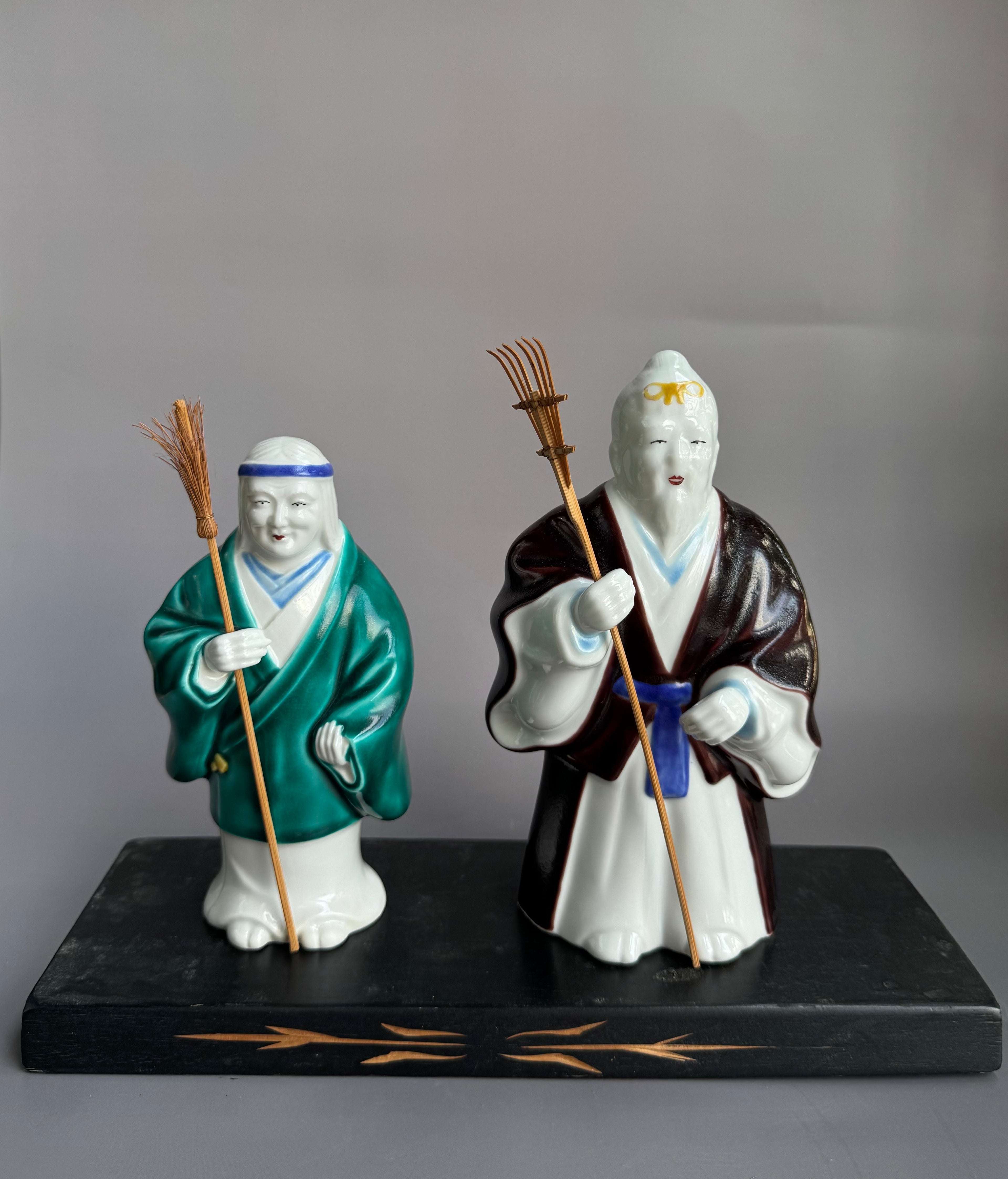 Two figurines on a black base against a gray background