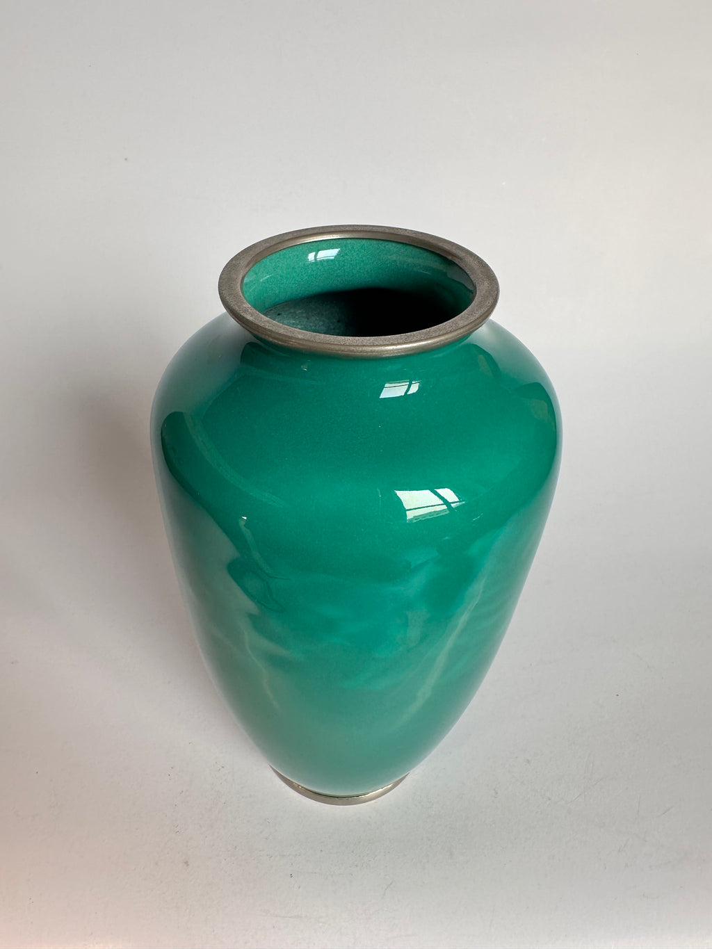Green ceramic vase with a metallic rim on a white background
