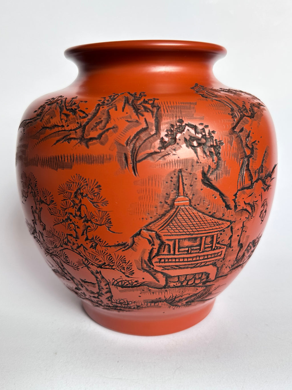 Terracotta vase with black engraved design on a white background