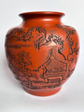 Terracotta vase with black engraved design on a white background