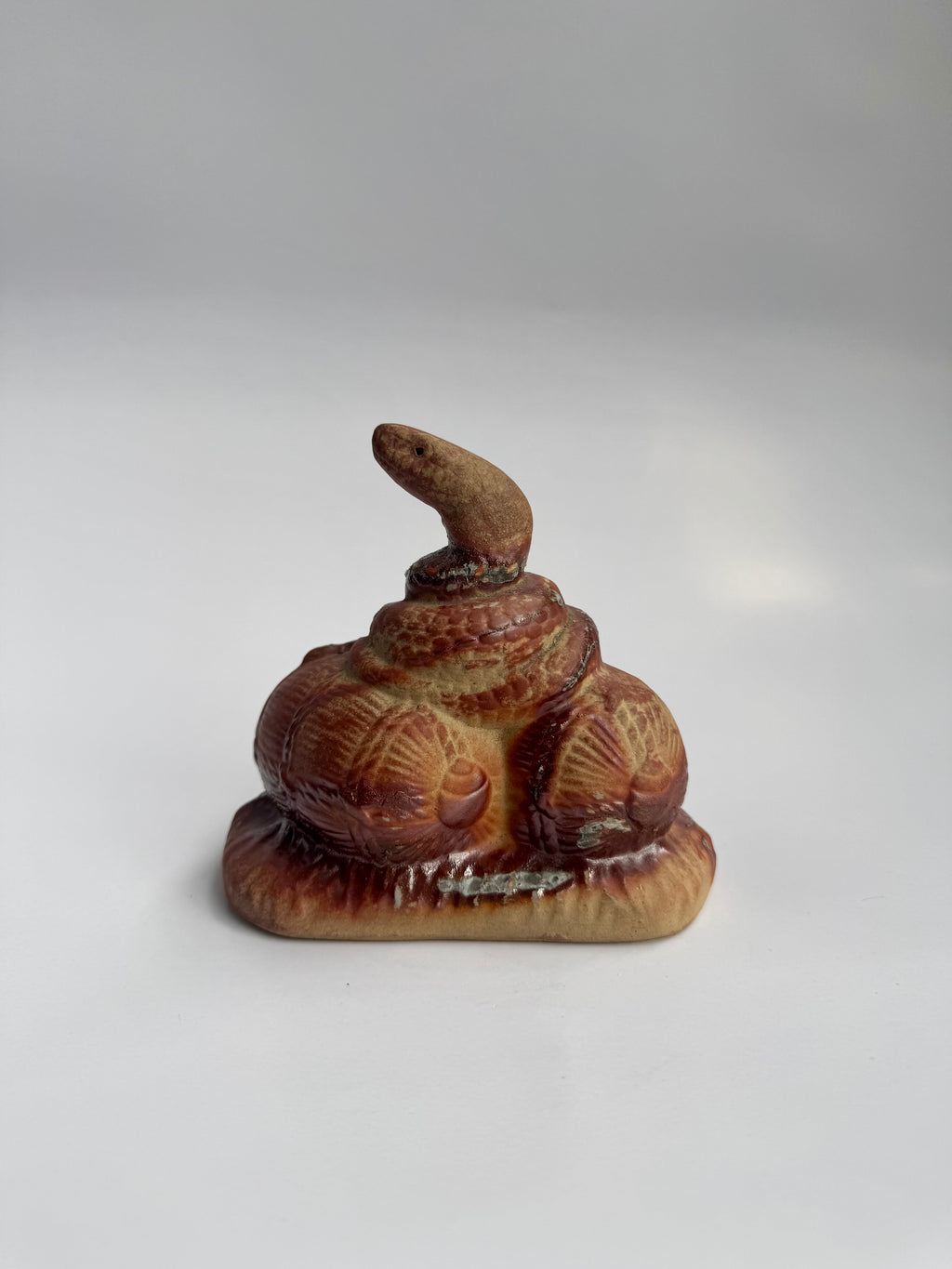 Small ceramic sculpture of a stylized figure on a plain background
