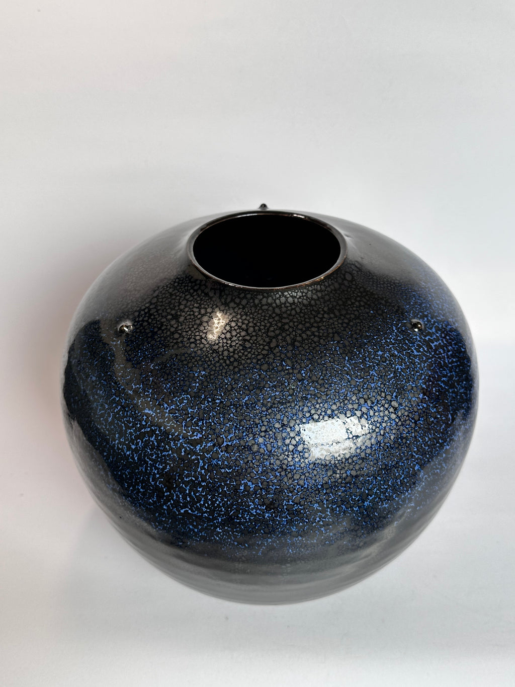 Black and blue speckled vase on a white background