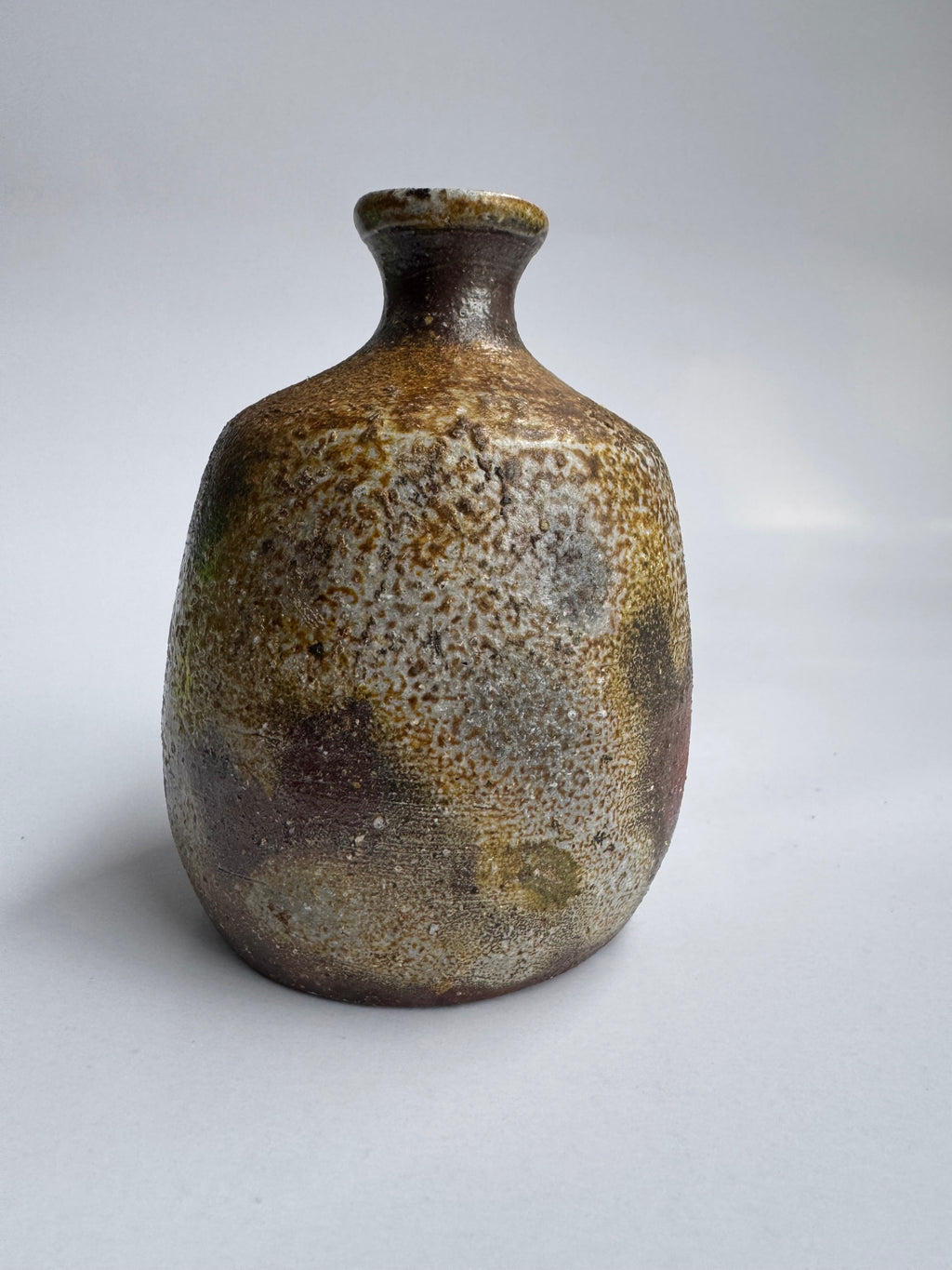 Brown ceramic vase with textured surface on a white background