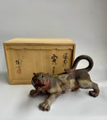 Vintage tiger figurine in front of a wooden box with Japanese text on a white background