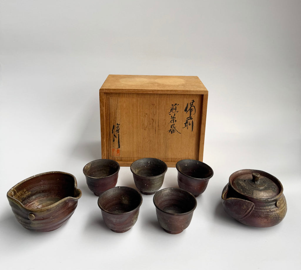 Set of six brown ceramic tea cups and a lid with a wooden box on a white background
