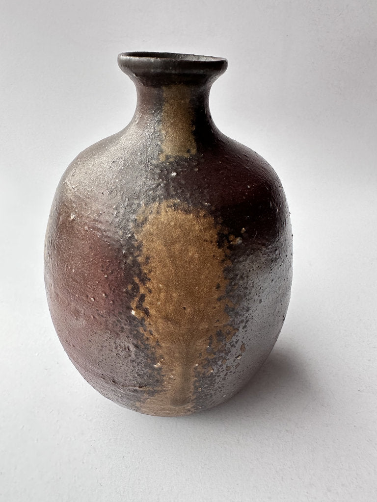 Ceramic vase with brown and black glaze on a white background
