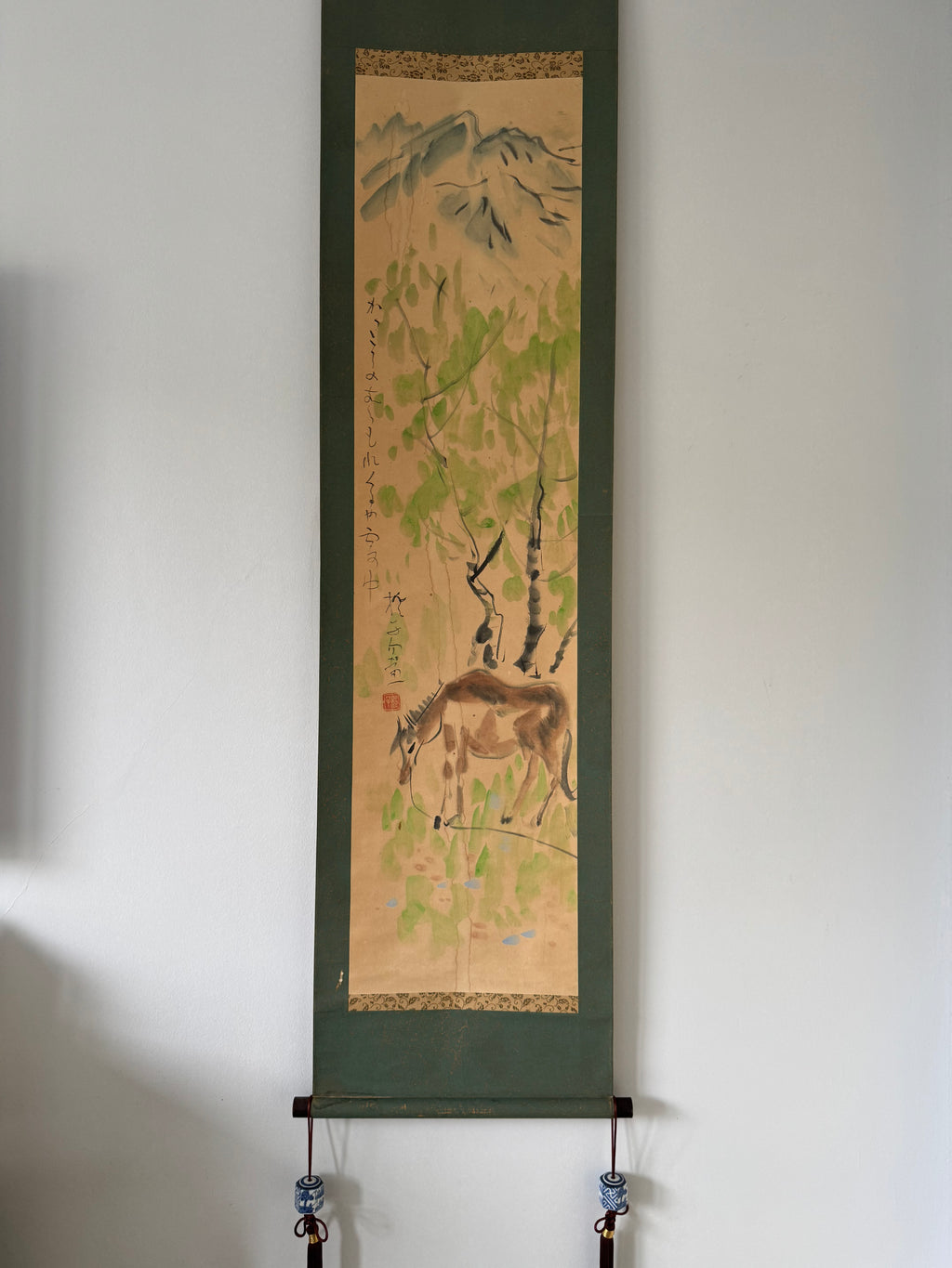 Traditional scroll with nature-themed artwork on a white wall