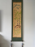Traditional scroll with nature-themed artwork on a white wall
