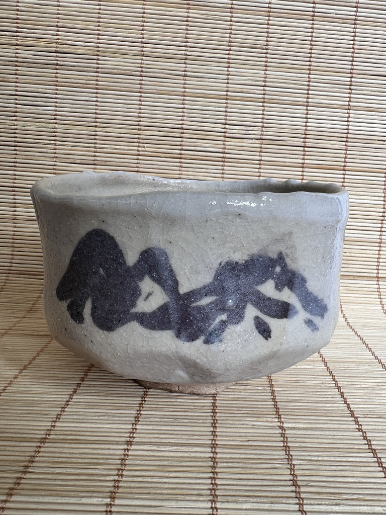 Ceramic bowl with black text on a woven mat