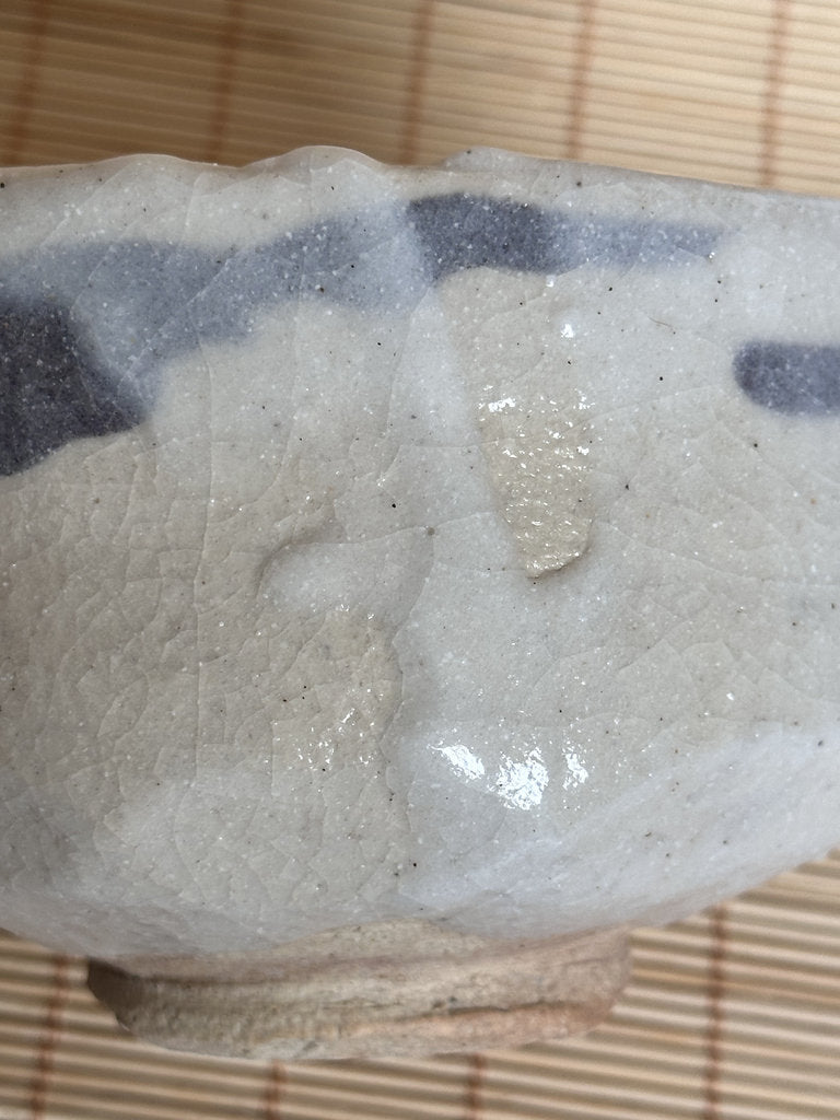 Close-up of a piece of white and gray stone on a woven mat background