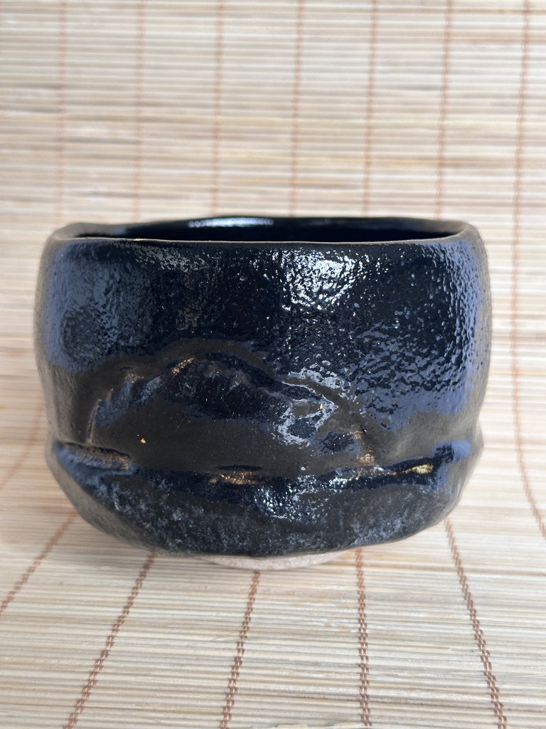 Black ceramic cup on a woven mat