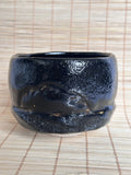 Black ceramic cup on a woven mat