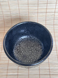 Blue ceramic bowl with textured surface on a woven mat