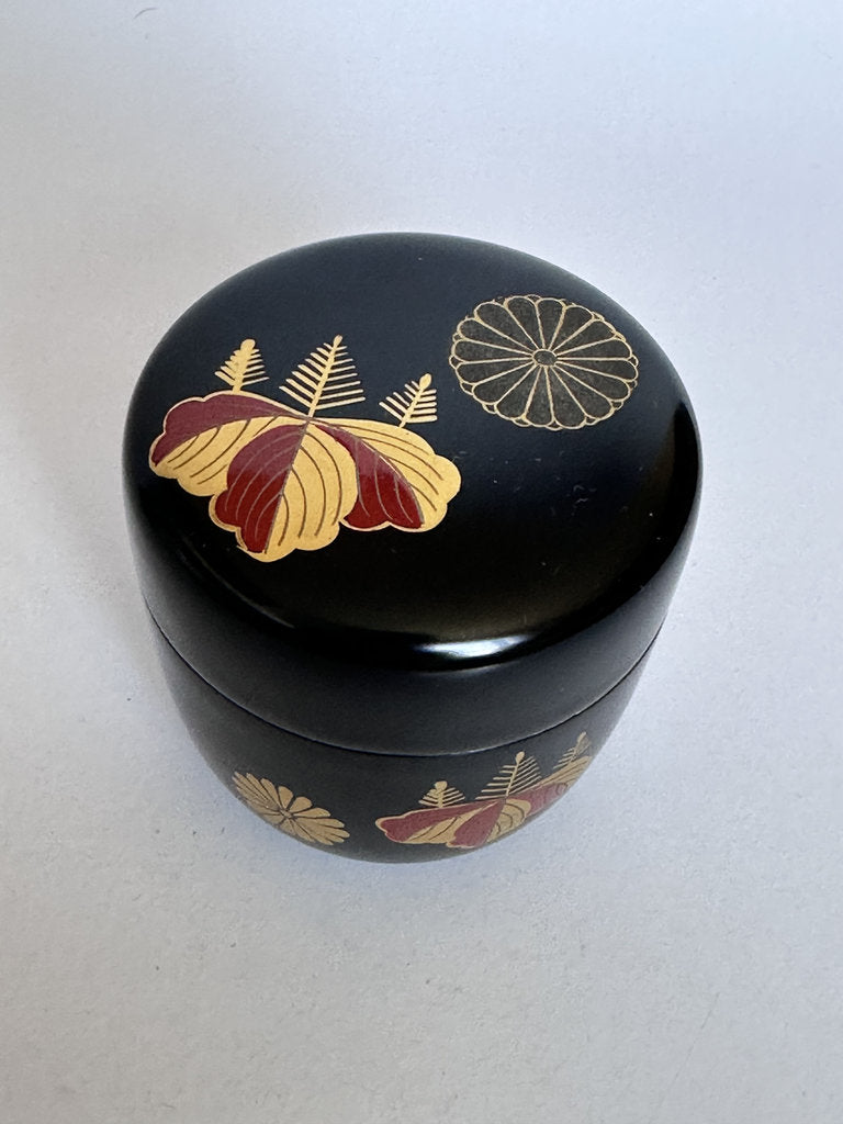 Black decorative container with floral patterns on a white background