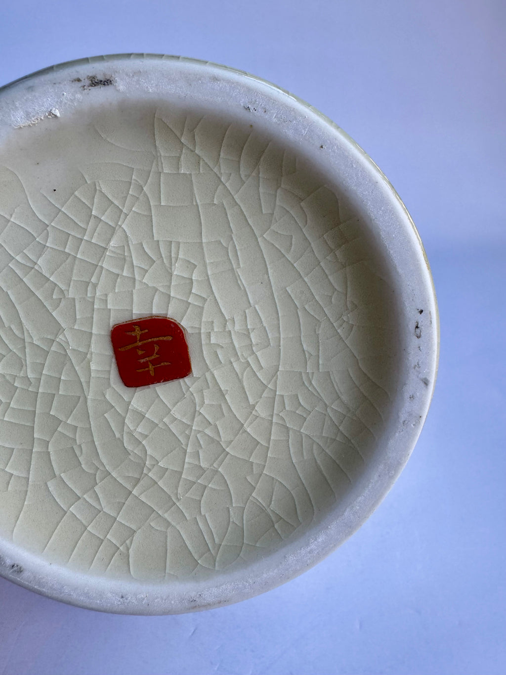 White ceramic bowl with textured surface and red stamp on a light purple background