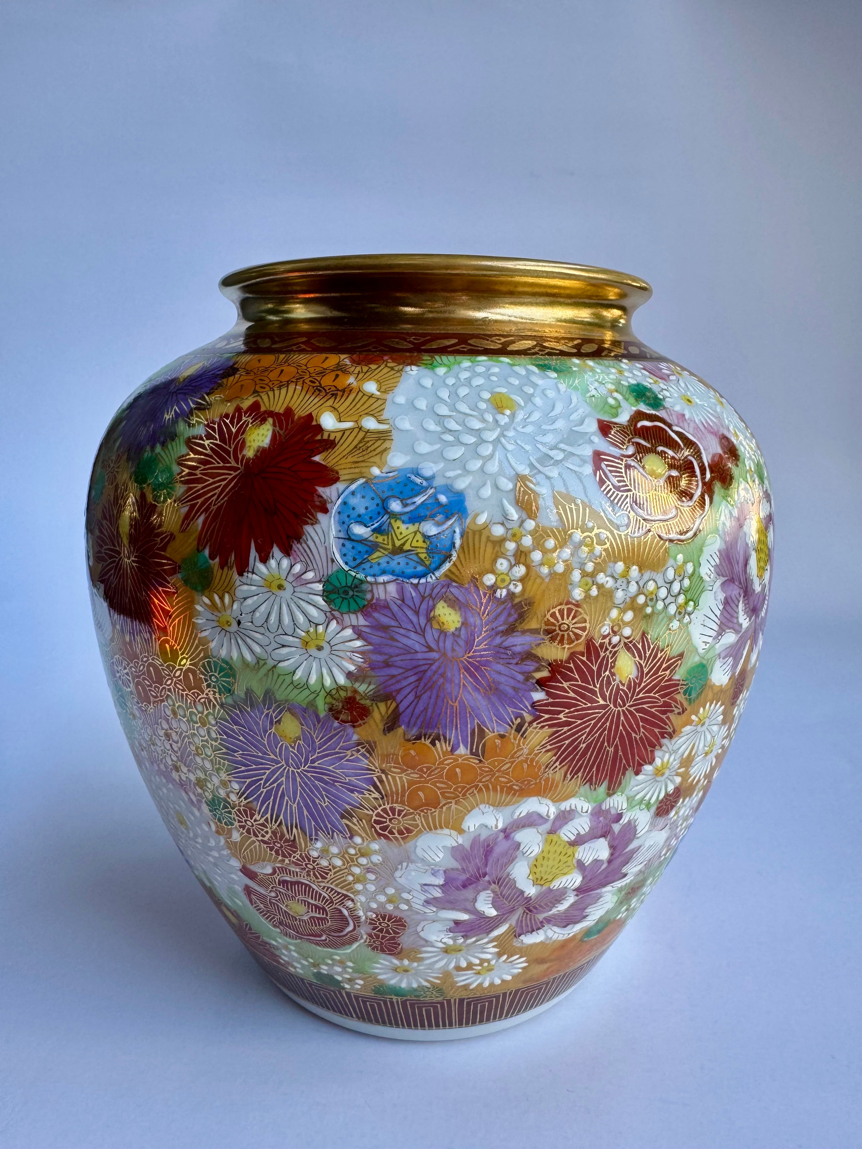 Decorative vase with floral patterns and a gold rim on a light gray background