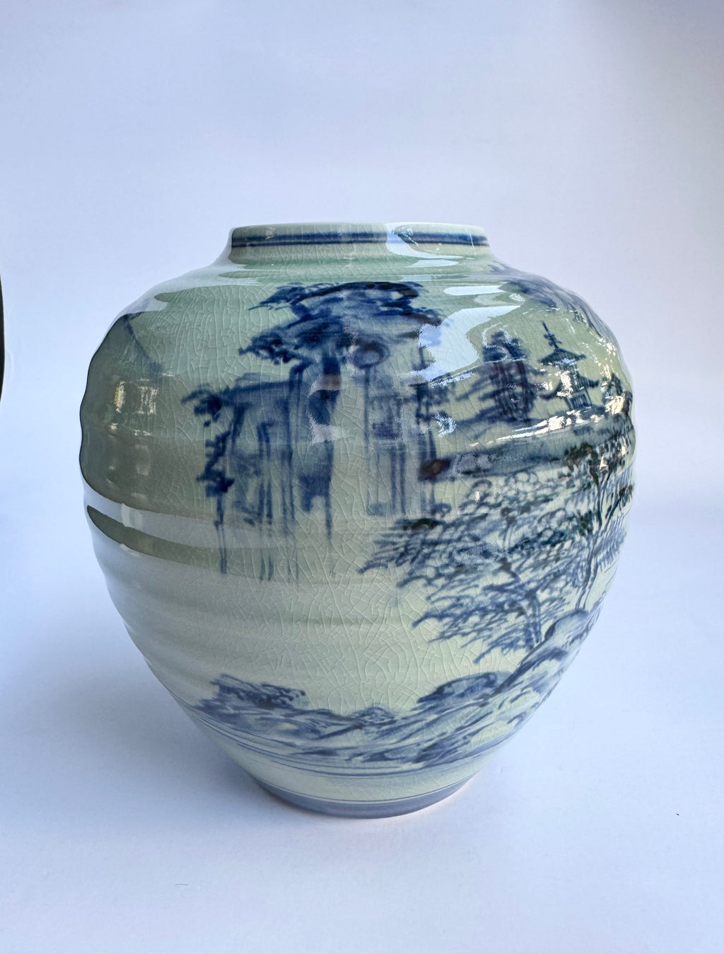 Ceramic vase with blue and white landscape design on a white background