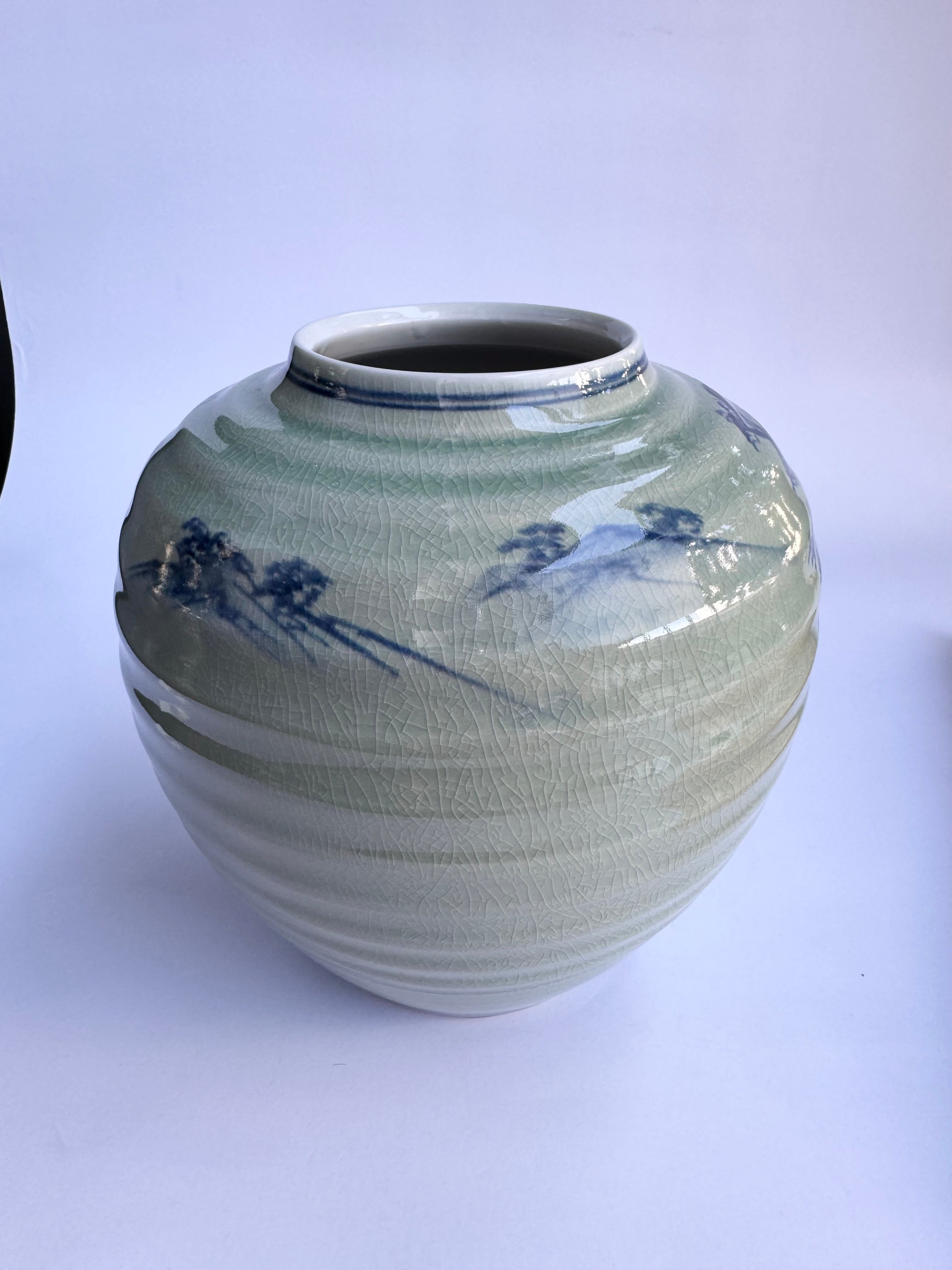 Green ceramic vase with blue floral patterns on a white background
