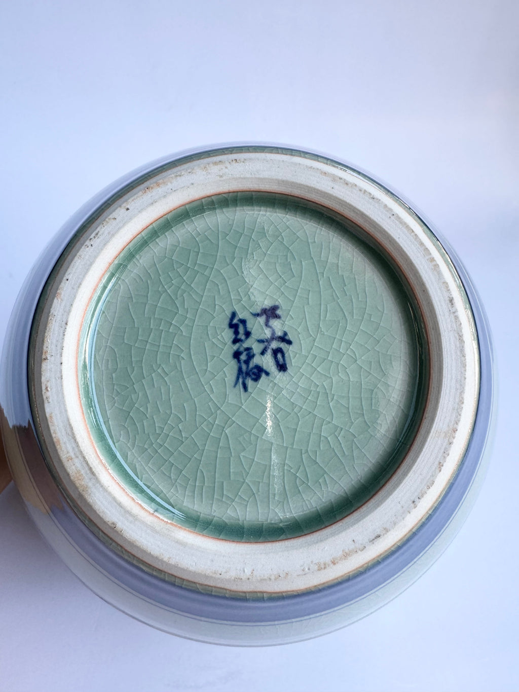 Close-up of a ceramic vase base with a signature on a white background