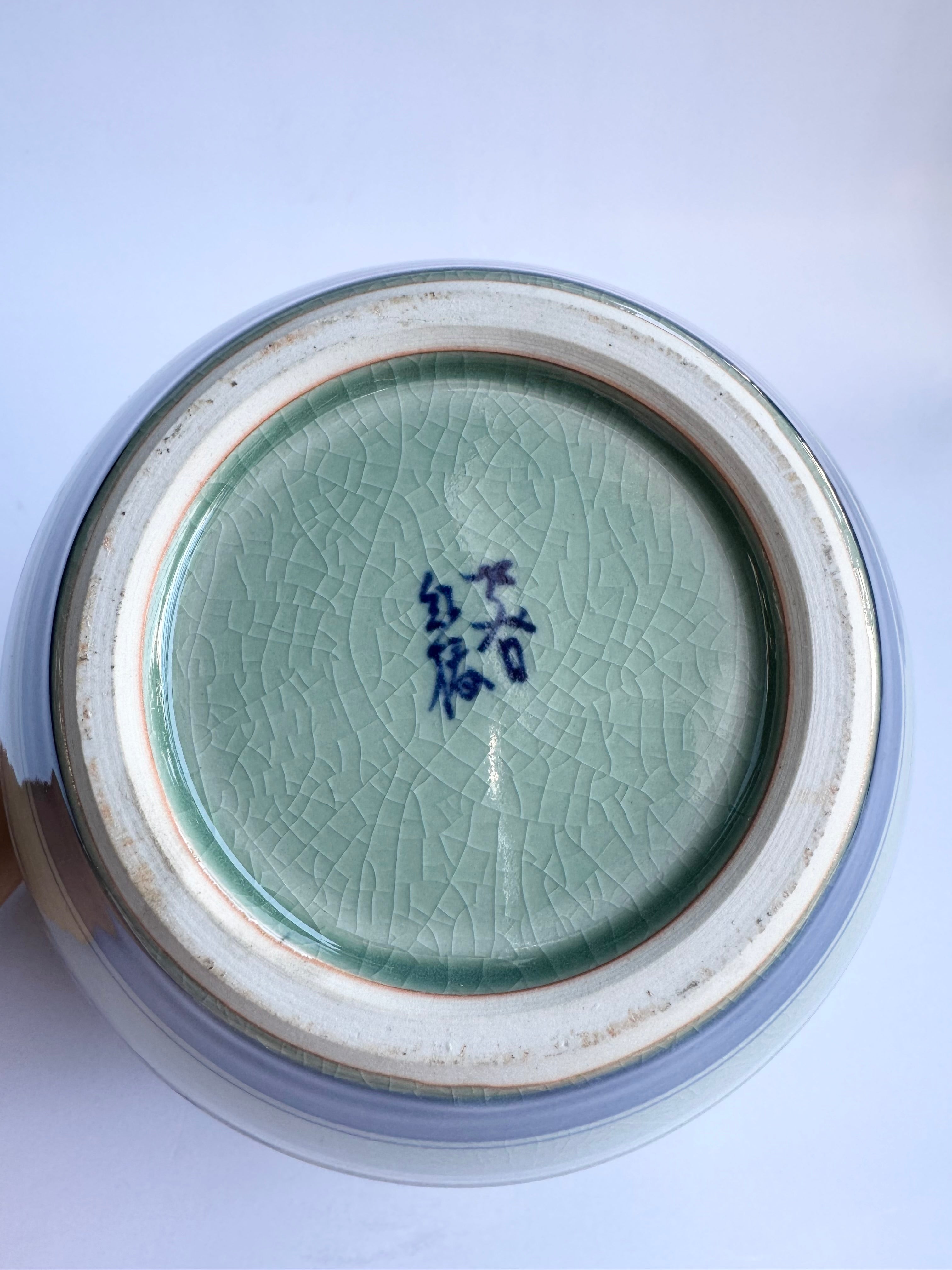 Close-up of a ceramic vase base with a signature on a white background