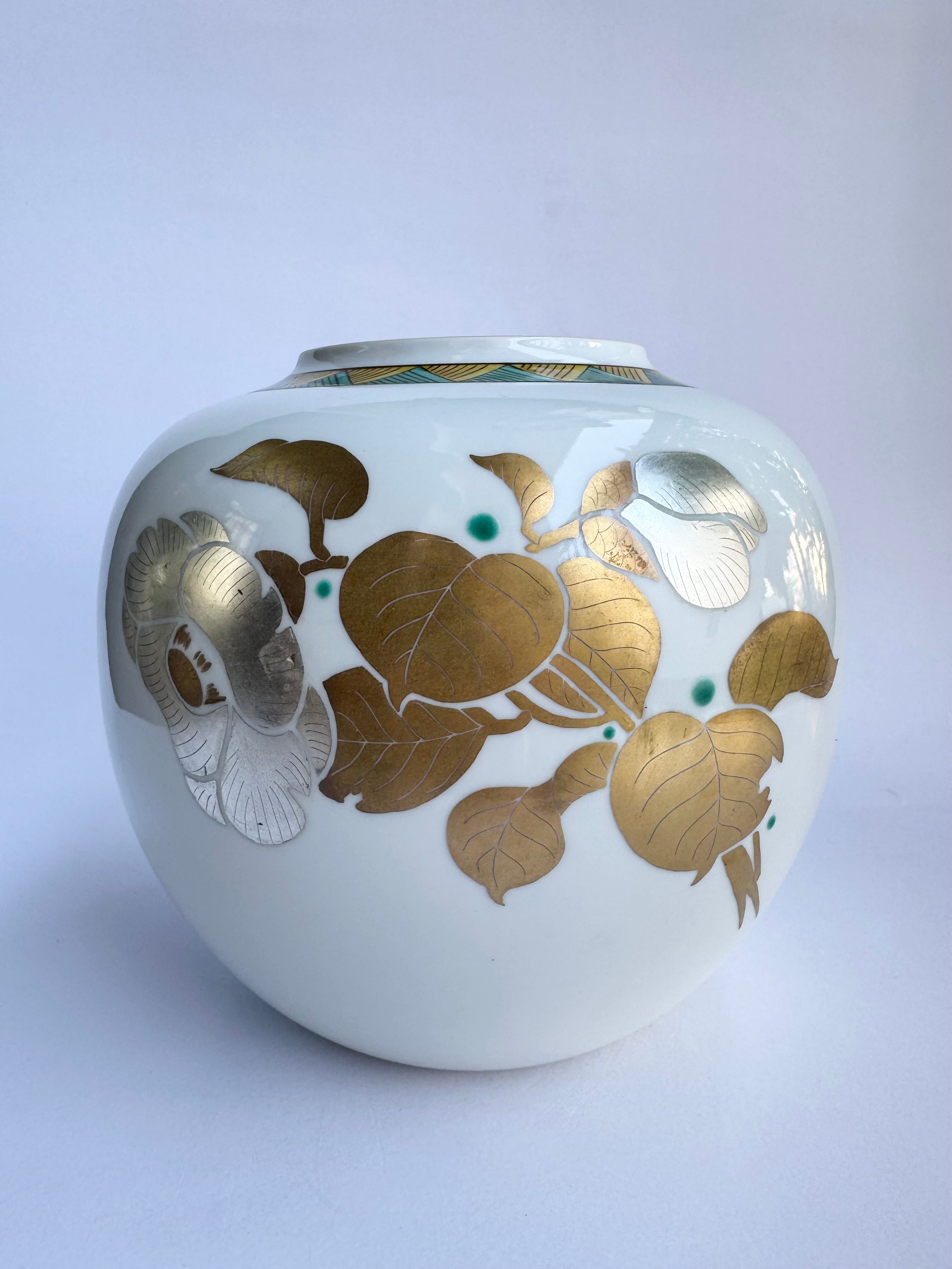 White ceramic jar with gold floral patterns on a light gray background
