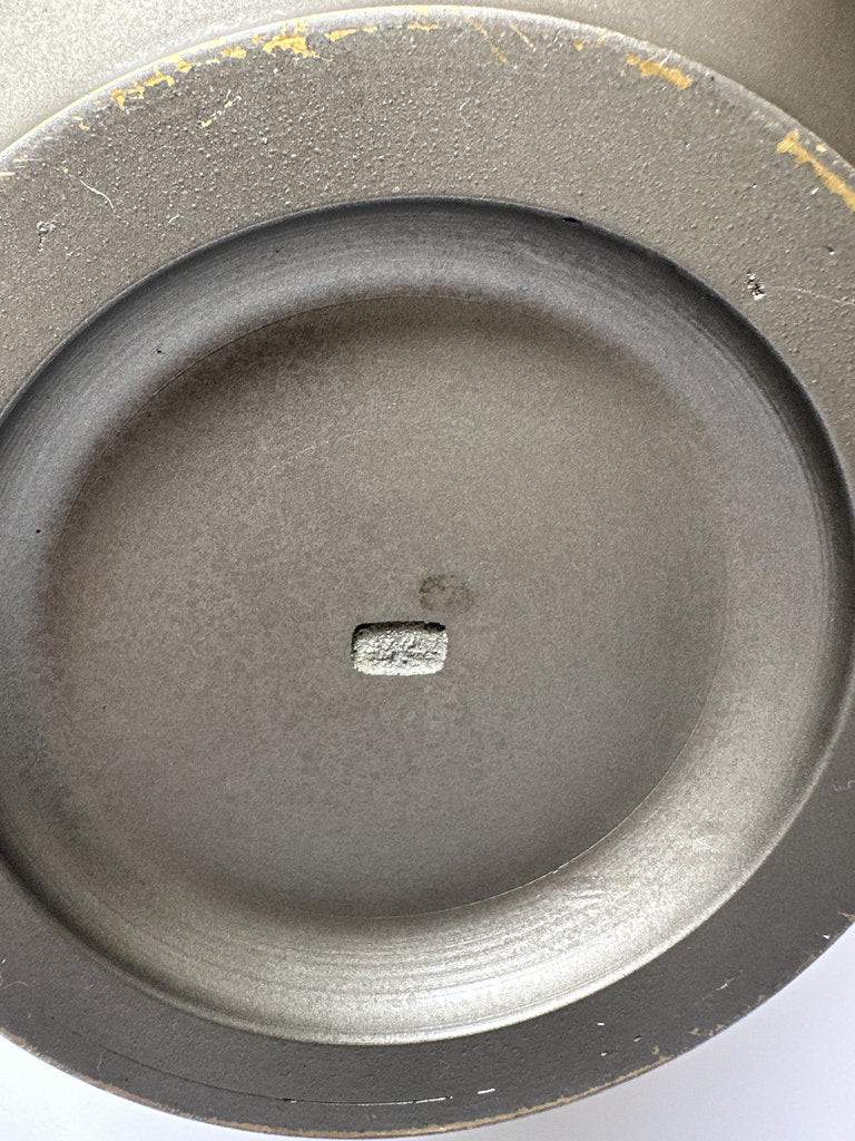 Close-up of a metallic object with a central square component on a white background