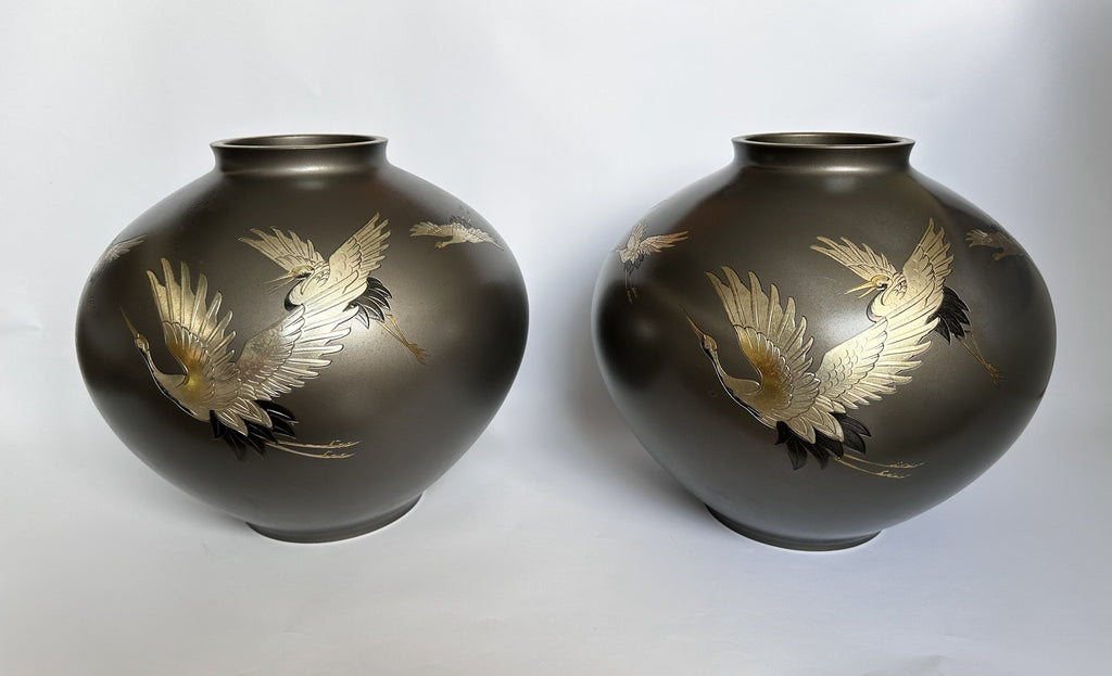 Two black vases with gold bird designs on a white background